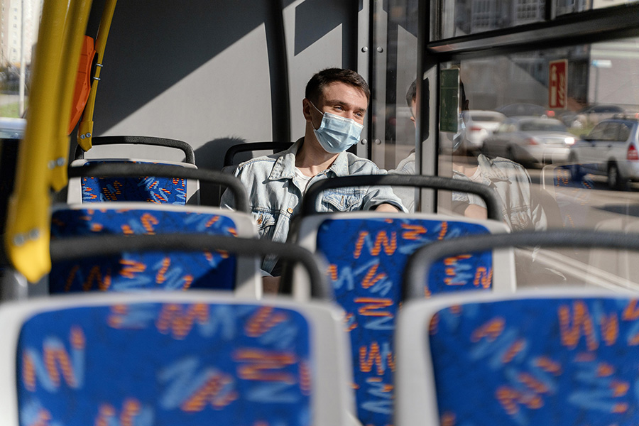 young-man-travelling-by-city-bus-wearing-surgical-mask